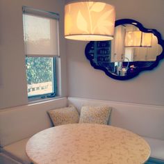 a dining room table with two chairs and a round mirror on the wall above it