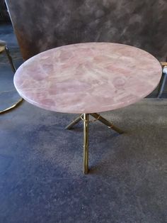 a pink marble table sitting on top of a metal stand in a room with chairs