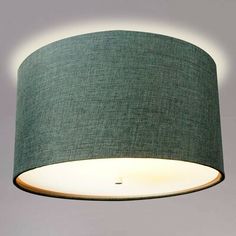 a green lampshade hanging from the ceiling with a light on it's side