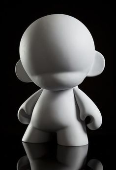 a small white toy sitting on top of a black surface with its eyes closed and hands behind it