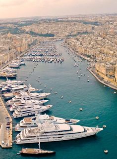 an aerial view of several boats docked in the water next to a city with lots of tall buildings