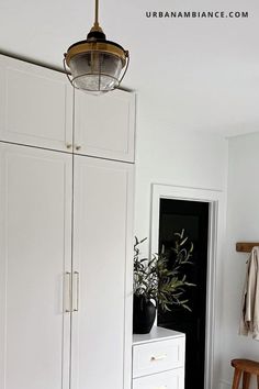 a room with white cupboards and a light hanging from the ceiling over it's head