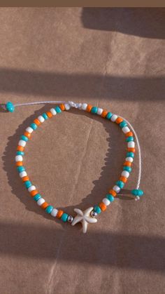 an orange, white and blue beaded bracelet with a starfish charm on it