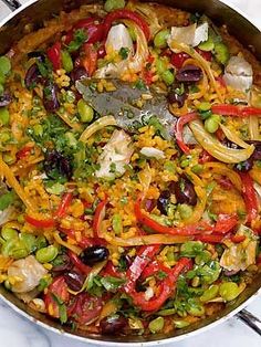 a pan filled with rice and vegetables on top of a table next to utensils