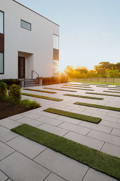 the sun is setting behind a building with grass growing on it's walkways