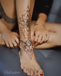 a woman's foot with tattoos on it and another person laying down behind her