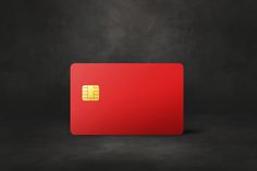 a red credit card sitting on top of a black table next to a gray wall