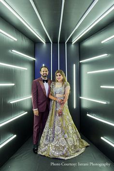 a man and woman posing for a photo in front of a wall with neon lights