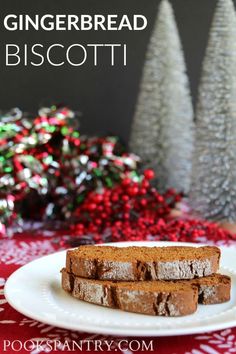 two slices of gingerbread biscotti on a white plate with christmas trees in the background