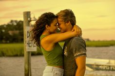 two people standing next to each other near the water