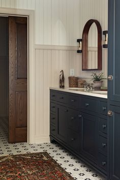 a bathroom with black cabinets and a rug on the floor in front of it's door