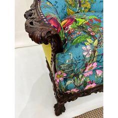 an ornate wooden chair with blue and pink floral upholstered fabric on the seat