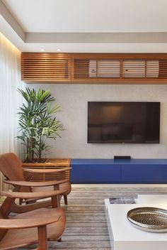 a modern living room with wooden furniture and a flat screen tv mounted on the wall