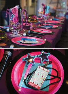 the table is set up with pink plates and black napkins, silverware, and star decorations