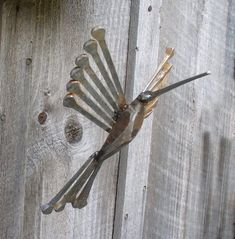 a bunch of forks stuck in the side of a wooden fence with nails sticking out of them