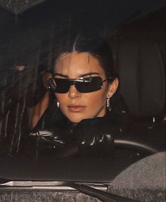 a woman wearing sunglasses sitting in the back seat of a car