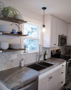 a kitchen with white cabinets and gray counter tops, stainless steel sink and dishwasher