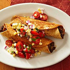 two quesadillas on a white plate topped with tomatoes and corn