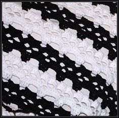 a black and white crocheted blanket is laying on top of a table cloth