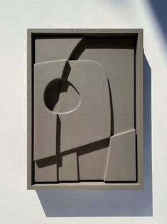 the shadow of a plant is cast on a white wall with a square shaped window