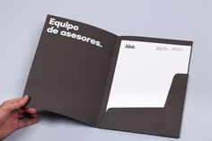 a hand holding an open book with spanish writing on the front and back pages in black