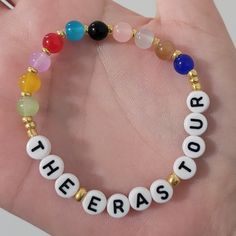 a hand holding a bracelet with the word therapy written on it and seven chakra beads