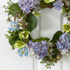 a wreath with blue and green flowers hanging on a door