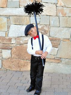 a young boy dressed in black and white holding a stick