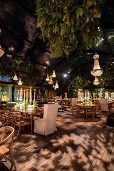 an indoor dining area with tables, chairs and hanging lights in the middle of it