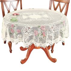 a round table with two wooden chairs and a lace doily on the tablecloth