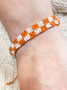 This Beaded Orange and White Checkerboard Adjustable Bracelet adds an eye-catching touch of color to any ensemble. The intricate beaded design is composed of alternating orange and white checks, creating a stunning statement piece. With an adjustable band, it can be easily worn by anyone. Details: Beaded Bracelet Orange and White Checkerboard Adjustable Pull String Bracelet Sizes: One Size Colors: Orange and White Trendy Orange Beaded Bracelets With Letter Beads, Trendy Adjustable Orange Friendship Bracelets, Adjustable Orange Friendship Bracelets For Summer, Orange Beaded Bracelets With Letter Beads For Beach, Casual Orange Beaded Bracelets With Round Beads, Friendship Bracelets With Orange Round Letter Beads, Orange Beaded Friendship Bracelets For Beach, Orange Friendship Bracelets With Colorful Beads, Trendy Orange Friendship Bracelets With Colorful Beads