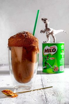 a glass filled with ice cream next to a can of milk and a toy horse