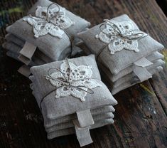 four pillows with white lace on them sitting on a wooden table