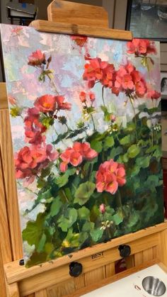 an easel with flowers painted on it in the process of being finished by someone