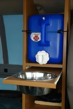 a blue water container sitting on top of a wooden shelf next to a metal bowl