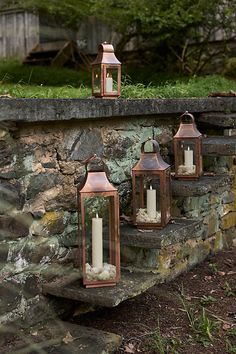 several lit candles are sitting on some steps in front of a stone wall with moss growing on it