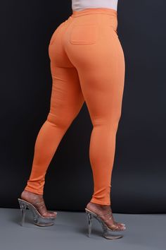 a woman wearing orange pants and high heels