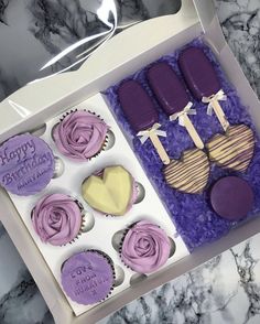 a box filled with cupcakes covered in purple frosting and decorated like hearts