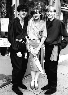 three people standing next to each other in front of a store