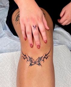 a woman with tattoos on her legs sitting on a bed