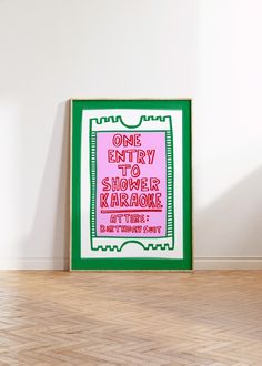 a green and pink poster sitting on top of a hard wood floor next to a white wall