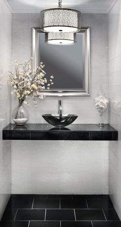 a black and white bathroom sink under a large mirror with flowers in the bowl next to it