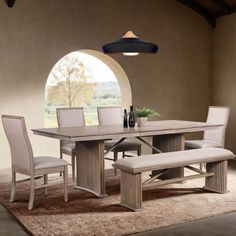 a dining room table and chairs with a bench in front of the window, next to an area rug