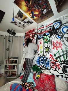 a woman standing on top of a bed next to a wall covered in graffiti