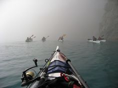 several people in kayaks paddling through the foggy water