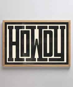 a black and white sign that says how on the wall above it is a wooden frame