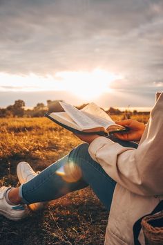 a person sitting in a field reading a book