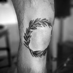 a black and white photo of a man's leg with a wreath tattoo on it