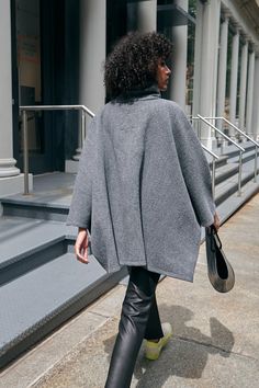 A stylish wool winter cloak, our Avery Cape is the ideal choice for heading out into the cold. Fashioned from Italian virgin wool and offered in fresh neutrals that pair well with any combination of clothing, this women’s wool cape is designed with a loose silhouette. Simple. Elegant. Cozy. Layer her over anything for an instant ready-to-go look. Avery's high collar has a side zipper for style and easy wear. This wool winter cape is lined for added warmth and comfort. | Astrid, in medium grey an Long Sleeve Wool Cape For Fall, Fall Merino Wool Outerwear, Oversized Wool Cape Coat For Fall, Oversized Winter Cape For Work, Oversized Cashmere Cape With Long Sleeves, Chic Cashmere Sweater Coat For Winter, Elegant Merino Wool Outerwear For Winter, Fall Workwear Poncho Cape, Elegant Merino Wool Outerwear For Fall