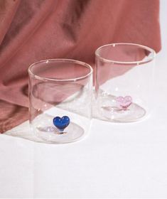 two glass cups with hearts in them sitting on a table